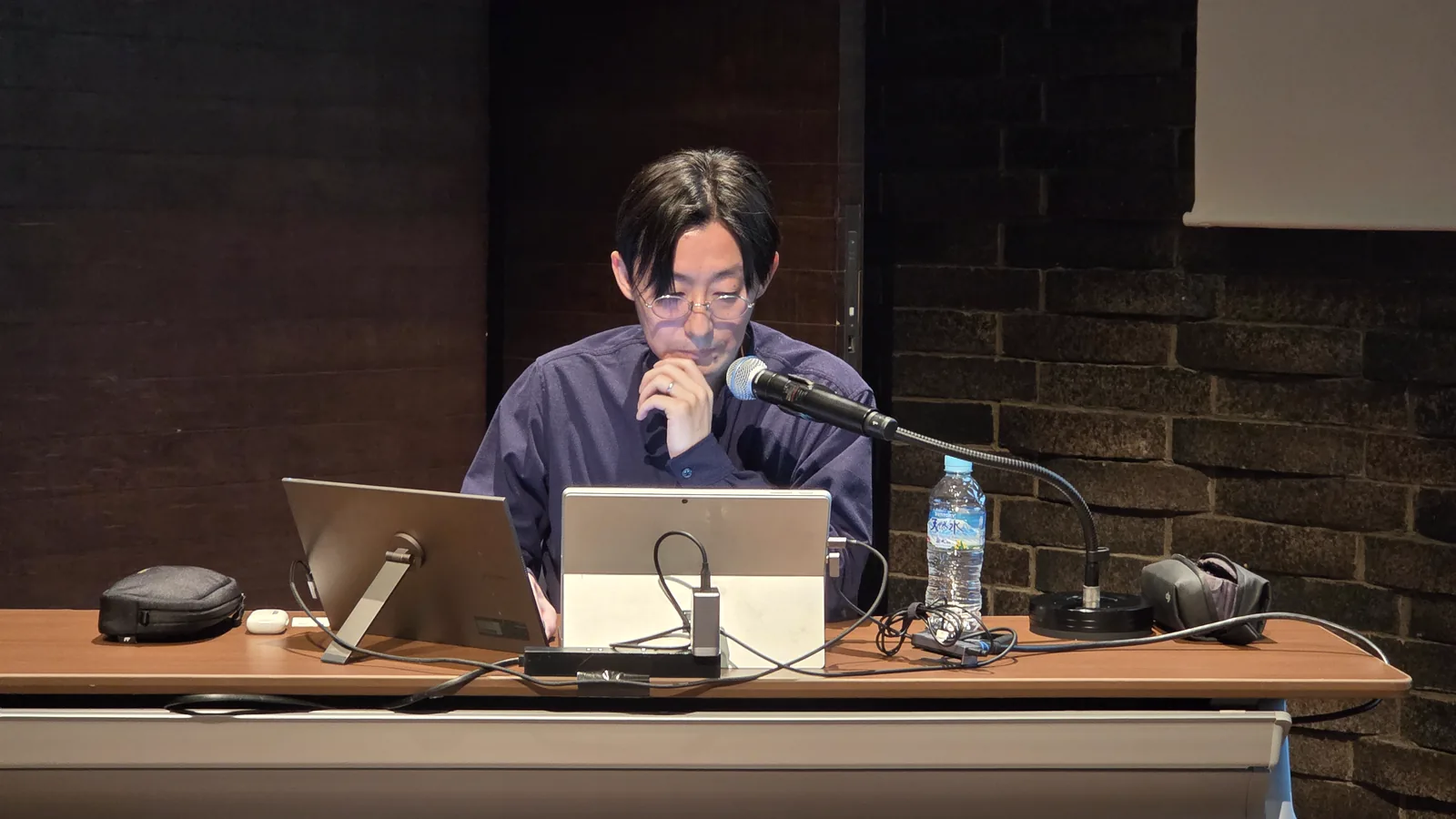 マイクの前でノートパソコンを操作しながら質問に答える講師