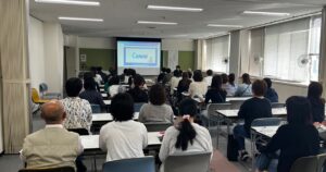 亀岡市総合福祉センターの講習室。スクリーンにCanvaの説明を映し、参加者の皆さまが前を向いて聞いている様子